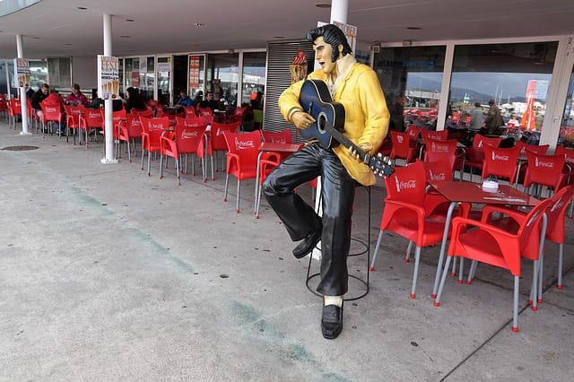 Lebensgrosse Elvis Figur mit schwarzer Akustik Gitarre vor einem Restaurant