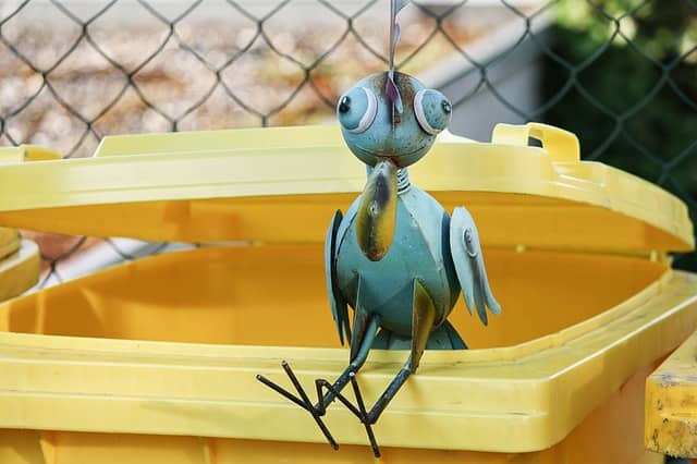 Gartenfigur Vogel auf Mülltonne